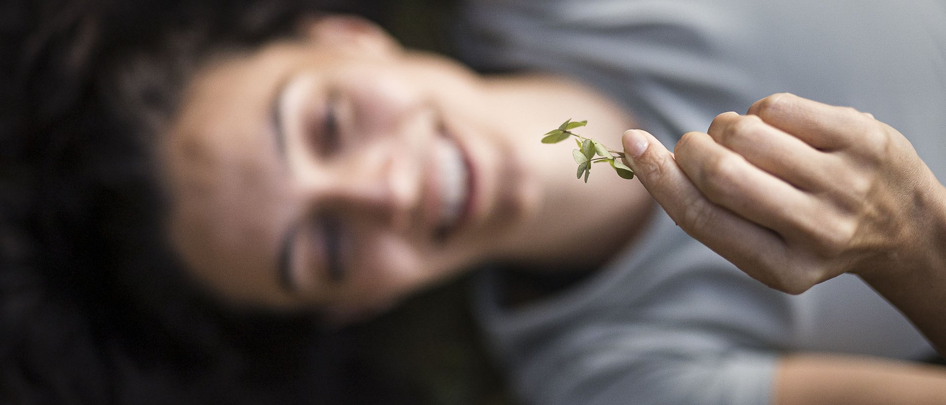Donna sdraiata sorridente che tiene una piccola foglia verde