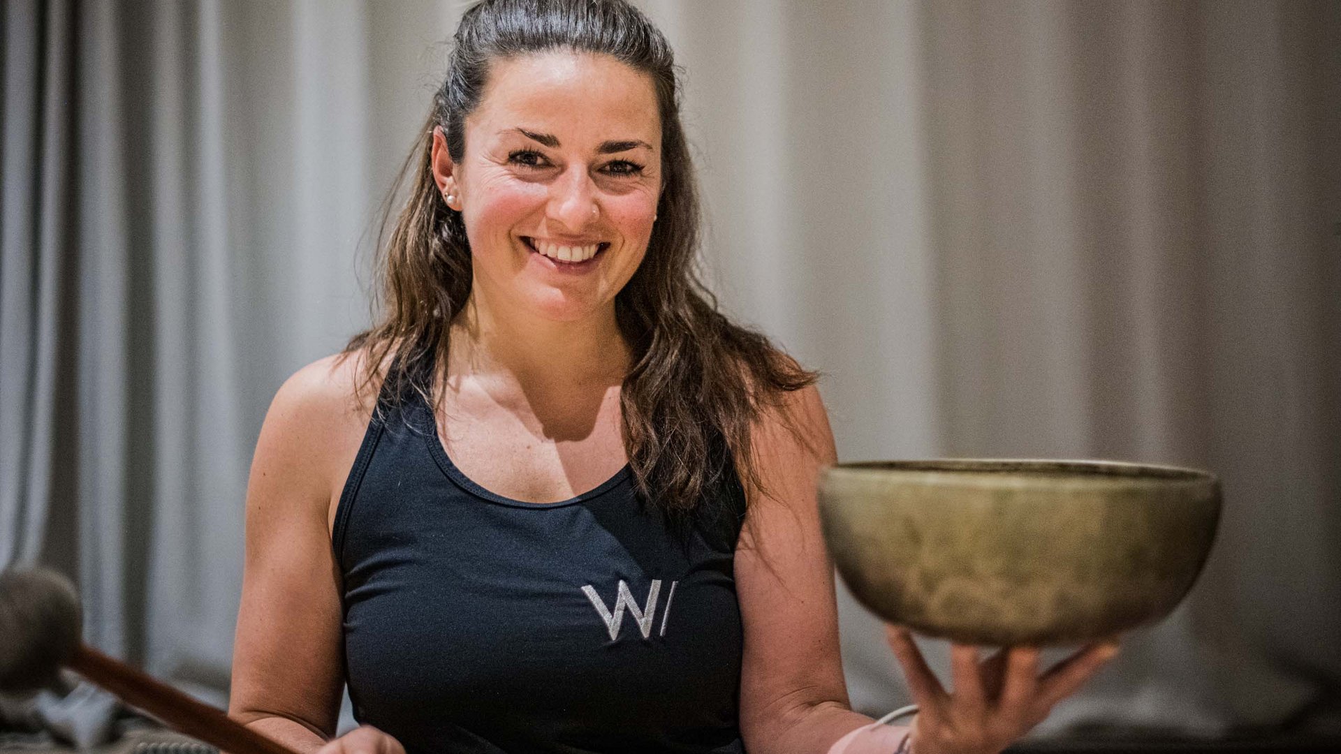 Donna sorride tenendo una ciotola tibetana e un bastone