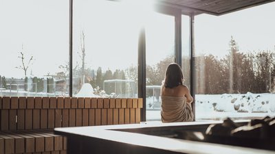 Photos from your hotel in Pfalzen in Val Pusteria/Pustertal Woman in sauna looking at snowy landscape through large windows