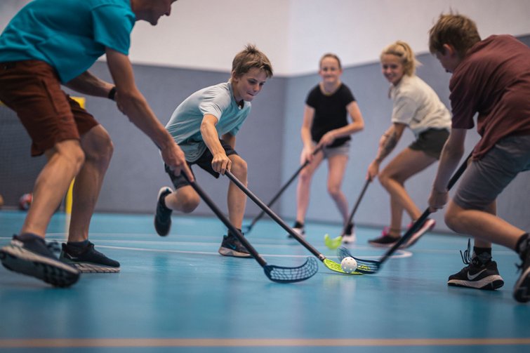 Bambini che giocano a floorball in palestra con mazze e pallina