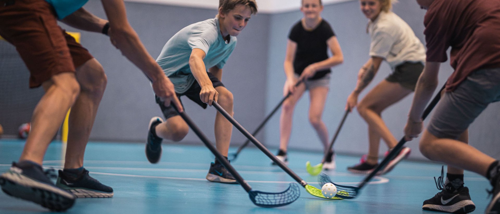 Kinder spielen Hallenhockey mit Stock und Ball in einer Sporthalle