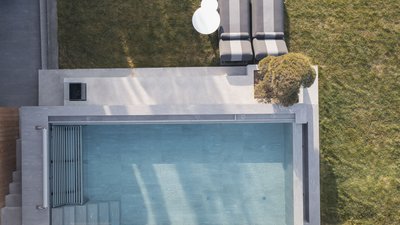 Vista aerea di una piscina moderna con due lettini e un tavolino nel giardino