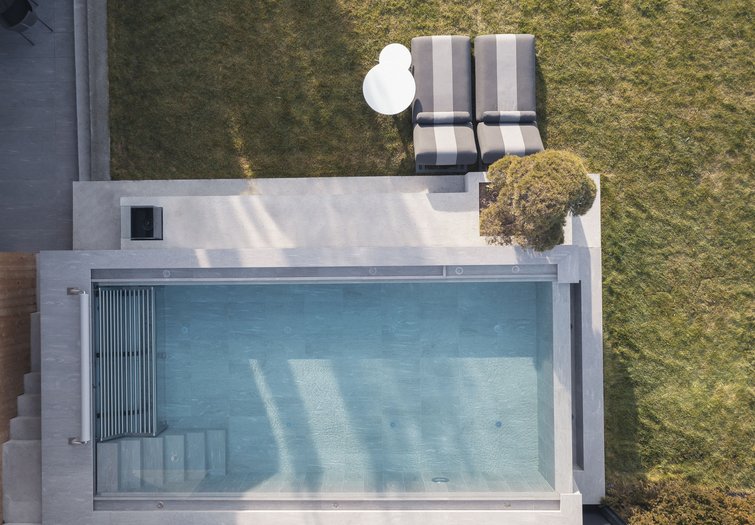 Your source of enrichment: our hotel at Mt Plan de Corones Aerial view of a modern pool with two loungers and a table in the garden