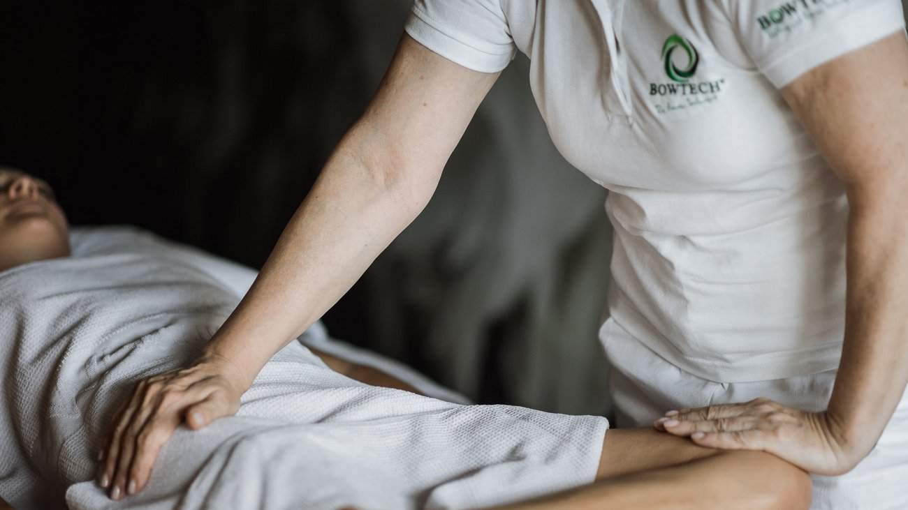 Therapeut massiert entspannten Patienten bedeckt mit weißem Handtuch