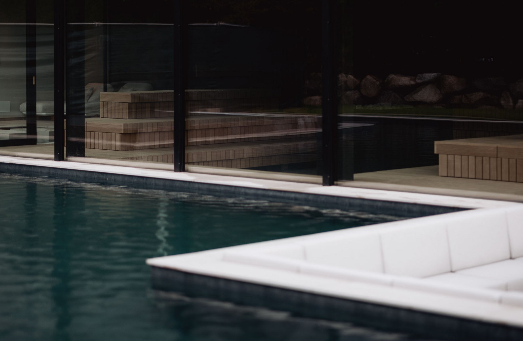 Angolo lounge moderno ai bordi di una piscina davanti a grandi finestre