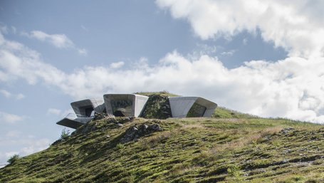Couple sitting on wooden bench hiking with modern mountain station in background