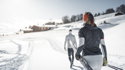 Due sciatori di fondo sulla neve, uno con gli sci sulla spalla