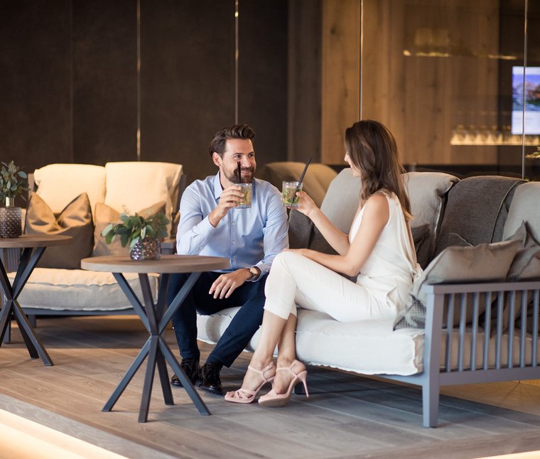 Coppia che beve cocktail e conversa in un moderno salotto