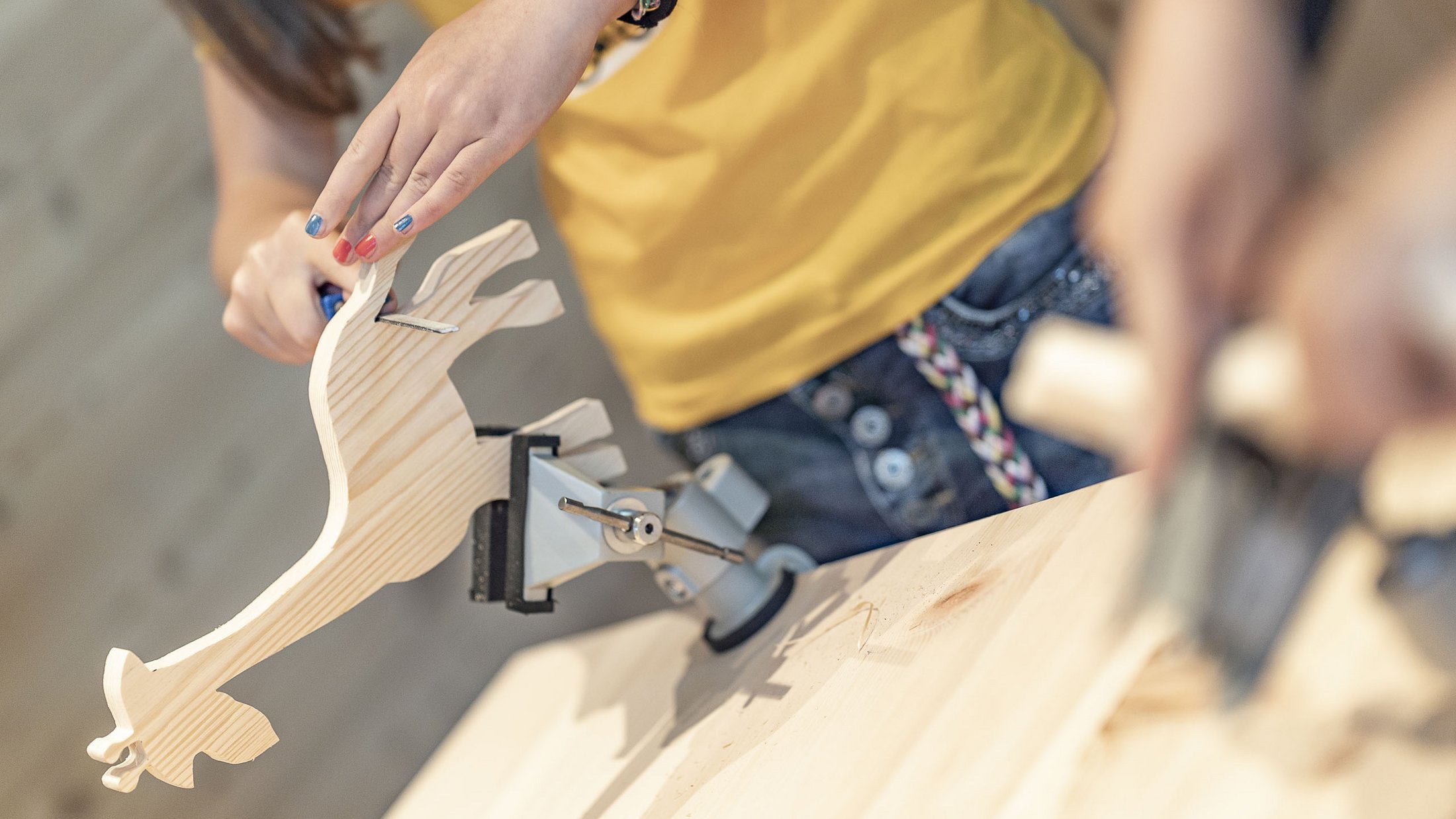 Persona avvita una vite in una sagoma di legno a forma di giraffa