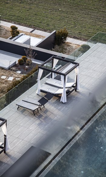 Terrazza moderna con lettini prendisole e baldacchino con tende bianche