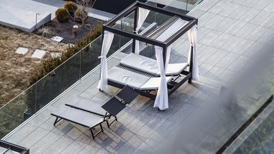 Terrazza moderna con lettini prendisole e baldacchino con tende bianche