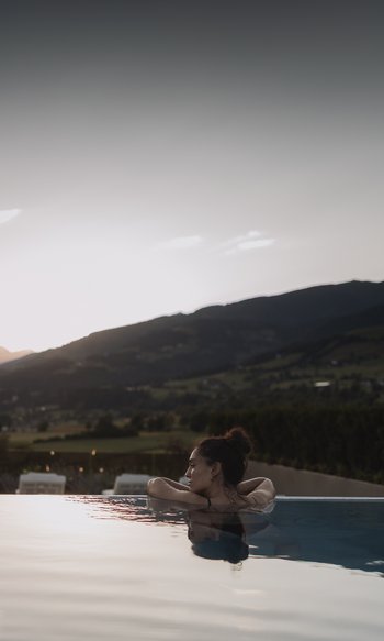 Die Heimat des Strahlens: Ihr Wellnesshotel in Südtirol Frau entspannt im Pool mit Bergblick bei Sonnenuntergang