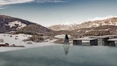 Eine regenerierende Auszeit vor Weihnachten Person sitzt am Rand eines beheizten Pools mit Blick auf verschneite Berge