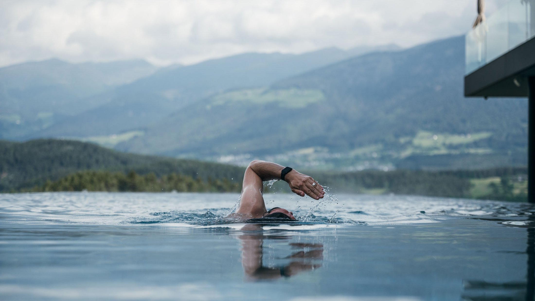 Persona che nuota in piscina a sfioro con vista sulle montagne