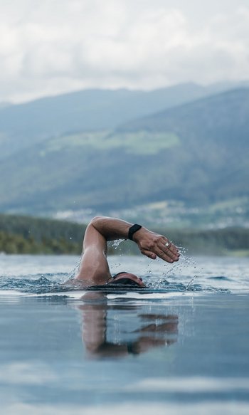 Person swimming in infinity pool with mountain view