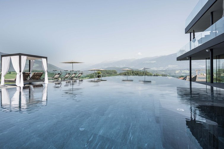 Piscina a sfioro con lettini e ombrelloni con vista sulle montagne