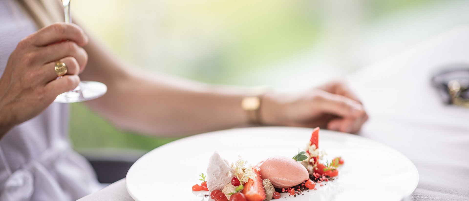Persona tiene calice di vino vicino a dessert elegantemente presentato su piatto bianco