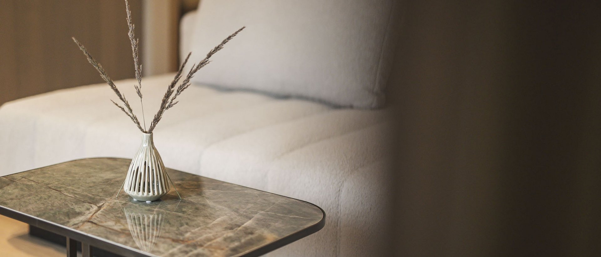 Vase mit Zweigen auf Couchtisch vor weißem Sofa in modernem Wohnzimmer