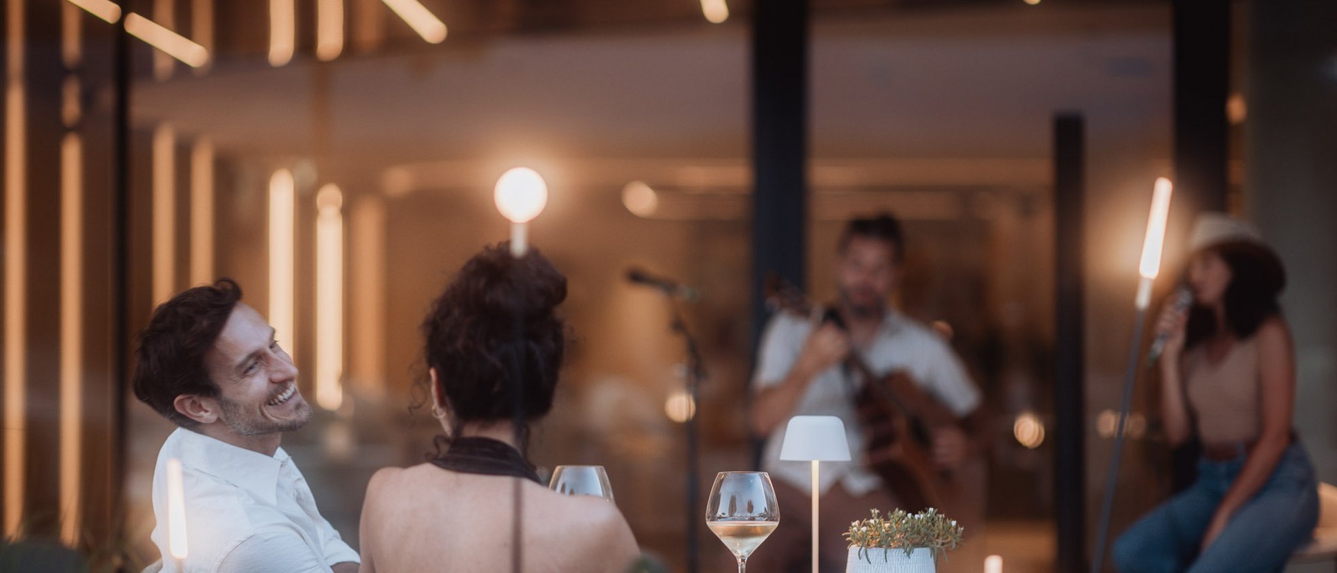 Couple enjoying live music with wine and modern ambient lighting