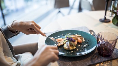 Persona che taglia un piatto di pesce raffinato su un piatto blu
