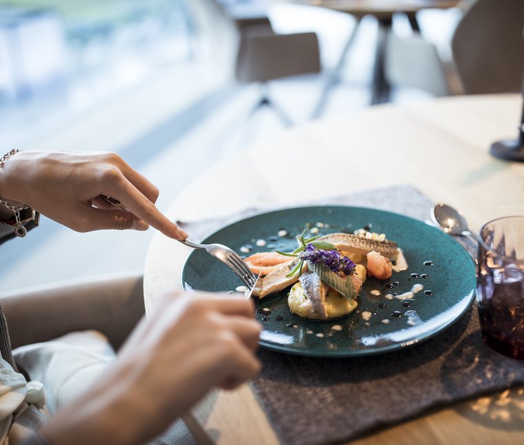 Persona che taglia un piatto di pesce raffinato su un piatto blu