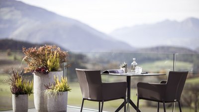 Tavolo e due sedie sulla terrazza con piante e vista sulle montagne