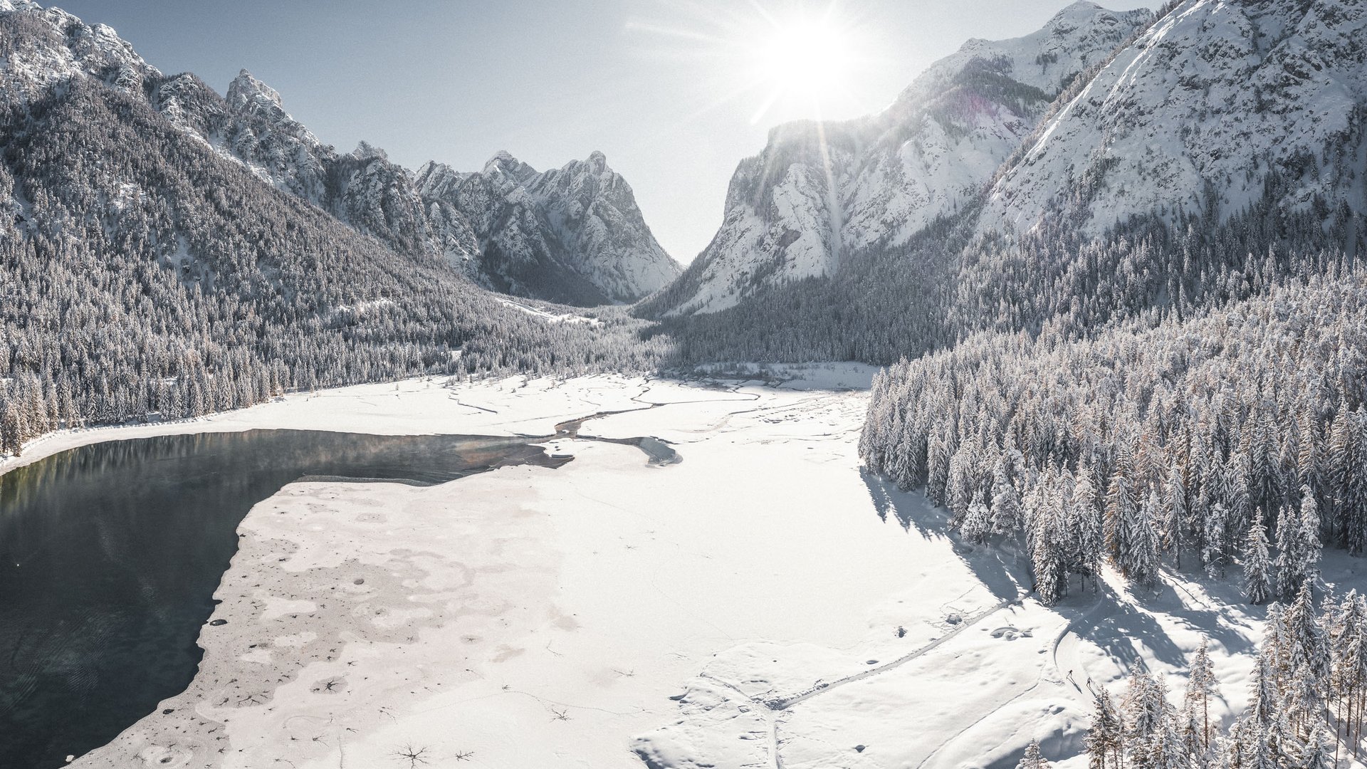 Das Reithotel in Südtirol für Pferdeliebhaber Verschneite Berglandschaft mit teilweise zugefrorenem See und Wäldern im Sonnenlicht