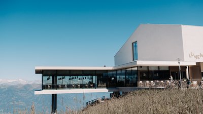 Edificio moderno con facciata di vetro su una collina sotto un cielo azzurro