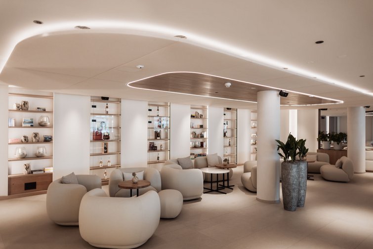 Die Kulinarik im Südtirol-Urlaub im Wellnesshotel Sonnenhof Modernes Lounge mit bequemen Sesseln, Tischen und beleuchtetem Holzdekor