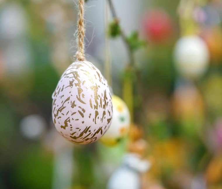 Eine regenerierende Auszeit vor Weihnachten Osterei mit goldenem Muster hängt an Faden vor unscharfem Hintergrund