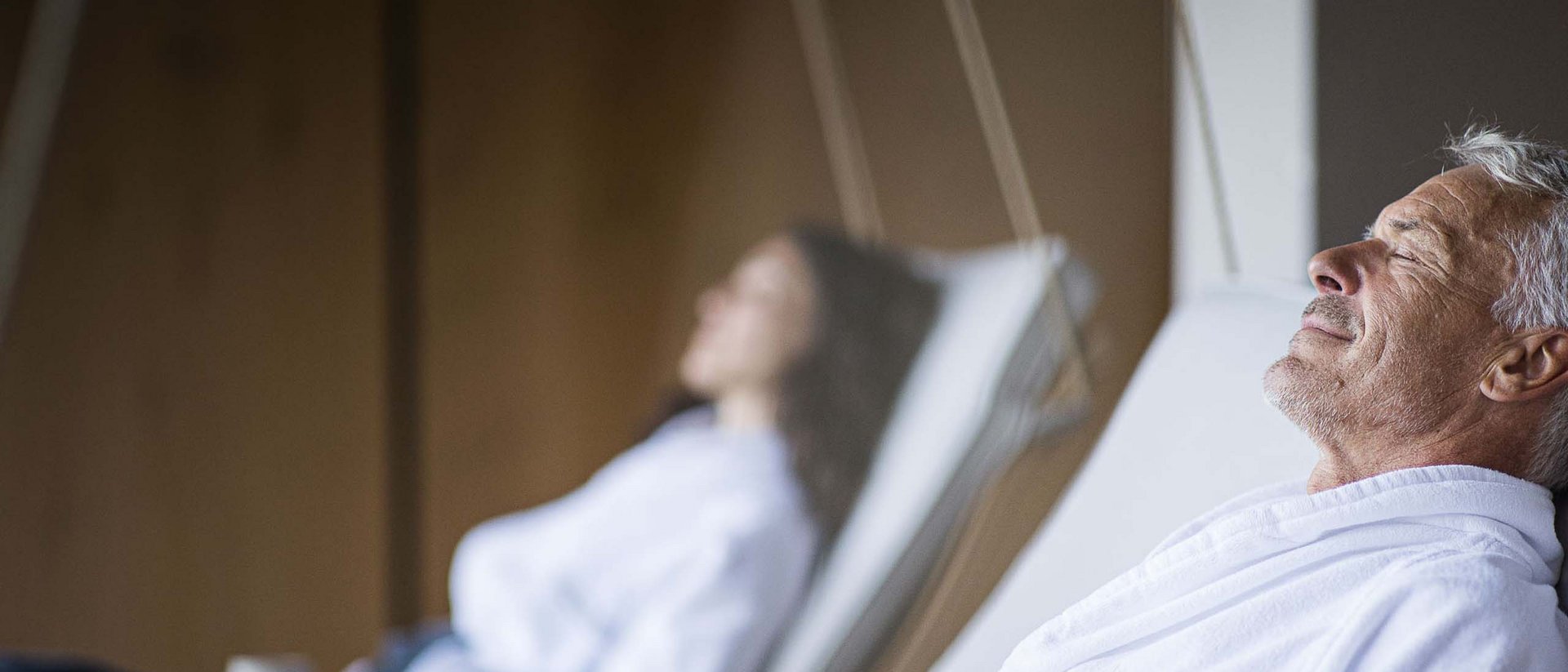 Uomo e donna anziani rilassati in accappatoi bianchi su sedie sospese