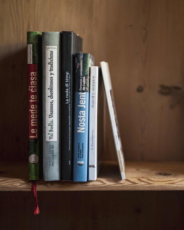 Libri su una mensola di legno accanto a una tenda bianca