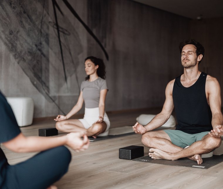 Persone meditano sedute su tappetini yoga in una stanza tranquilla