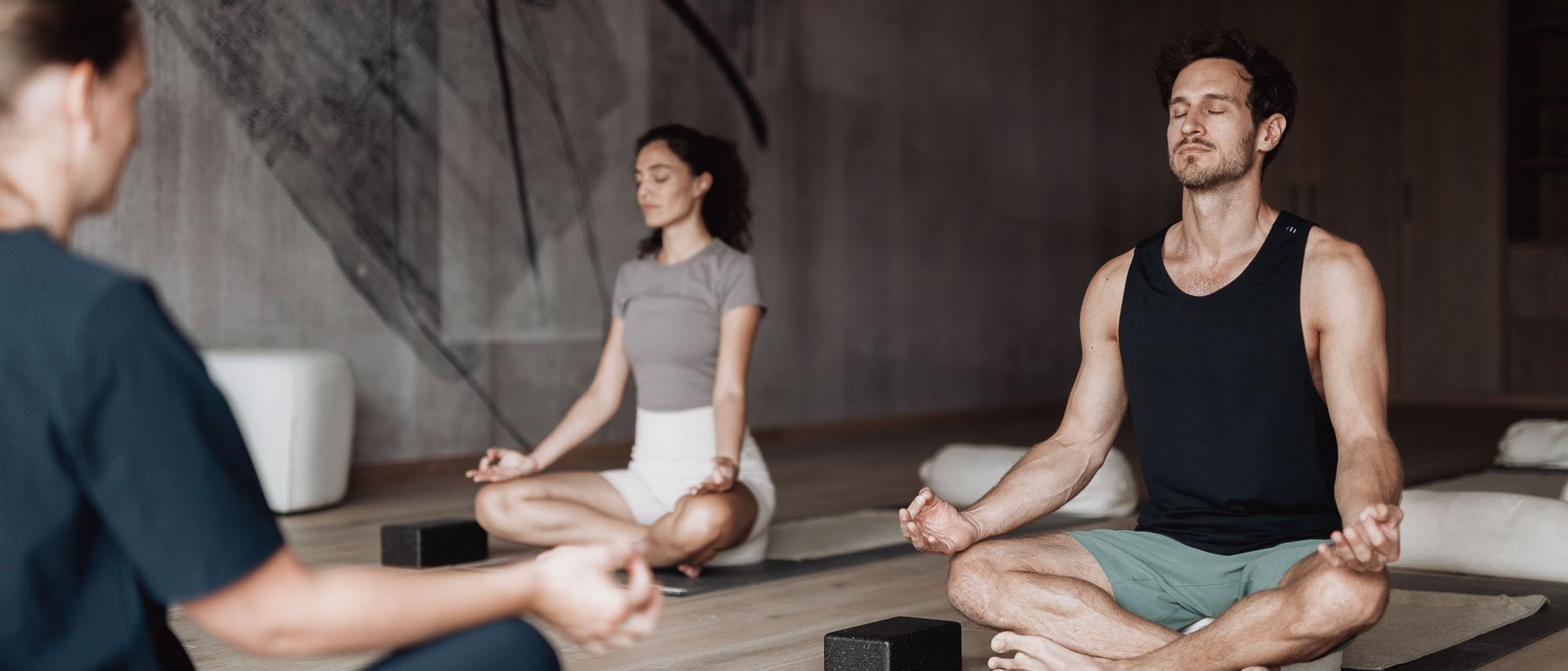 Persone meditano sedute su tappetini yoga in una stanza tranquilla