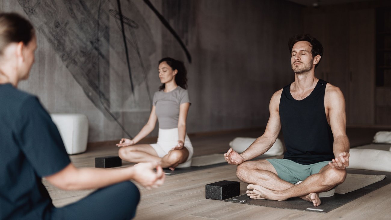 Personen meditieren sitzend auf Yogamatten in einem ruhigen Raum