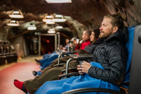 People relaxing in a cave on chairs with blankets and mugs