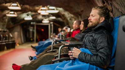 Persone che si rilassano in una grotta su sedie con coperte e tazze