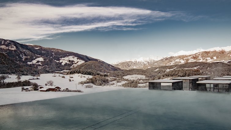 Heated outdoor pool with mountain view and snow-covered fields in winter