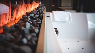 L’esclusività in foto: il nostro chalet in Alto Adige di lusso Vasca da bagno moderna accanto a camino con pietre ardenti