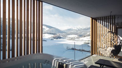 Balcone con vasca idromassaggio e sedia a dondolo con vista sulle montagne innevate