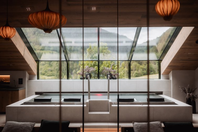 Modern spa bath with large tub and panoramic window showing mountain view