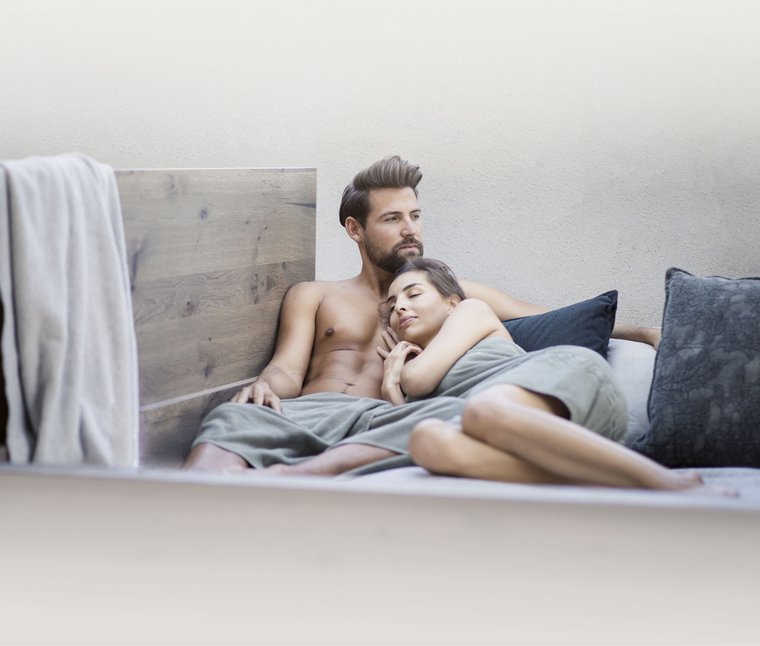 Paar entspannt zusammen auf einem Bett mit Kissen und Decke