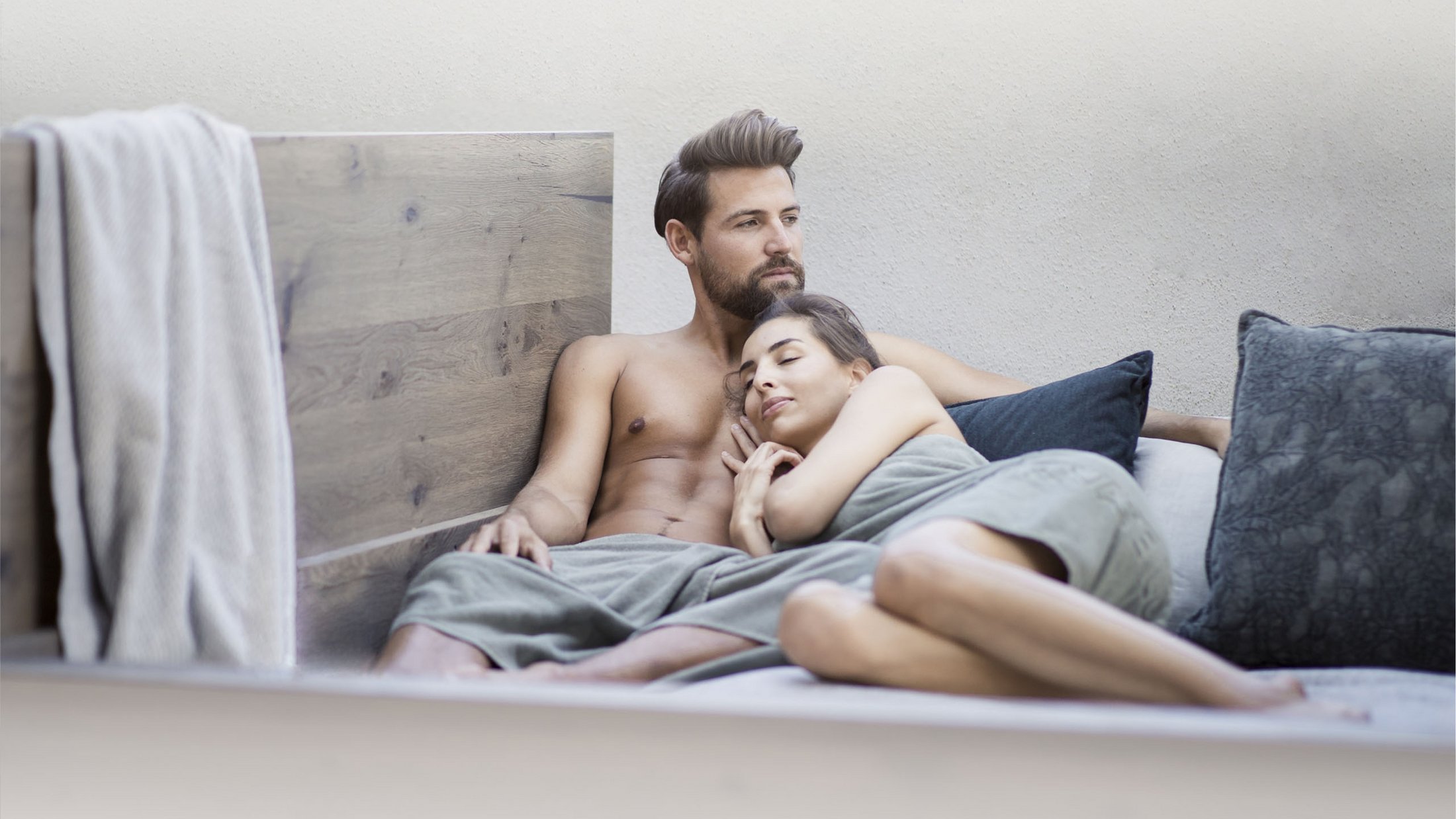 Couple relaxing together on a bed with pillows and blanket