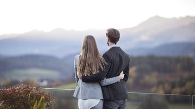 Coppia abbracciata che guarda un paesaggio montano sullo sfondo