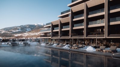 Photos from your hotel in Pfalzen in Val Pusteria/Pustertal Modern spa area with heated outdoor pool and loungers in front of snowy mountains