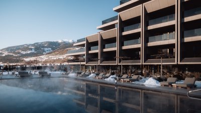 Photos from your hotel in Pfalzen in Val Pusteria/Pustertal Modern spa area with heated outdoor pool and loungers in front of snowy mountains