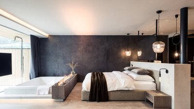 Camera moderna con vasca e camino integrato accanto al letto