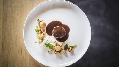 Piatto gourmet con carne, funghi e verdure su piatto bianco