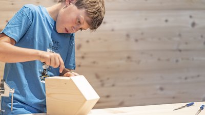 Ragazzo concentra il lavoro su un progetto in legno in laboratorio