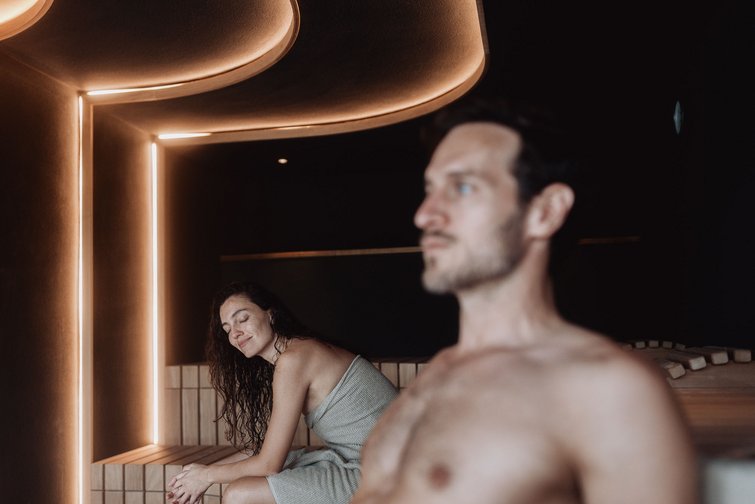 Donna e uomo rilassati in una sauna moderna con illuminazione soffusa